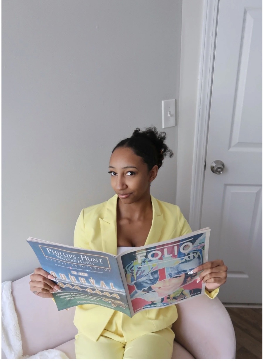 Trissa Ilise, founder of Interiors by Ilise, seated in a blush armchair holding an open design magazine
